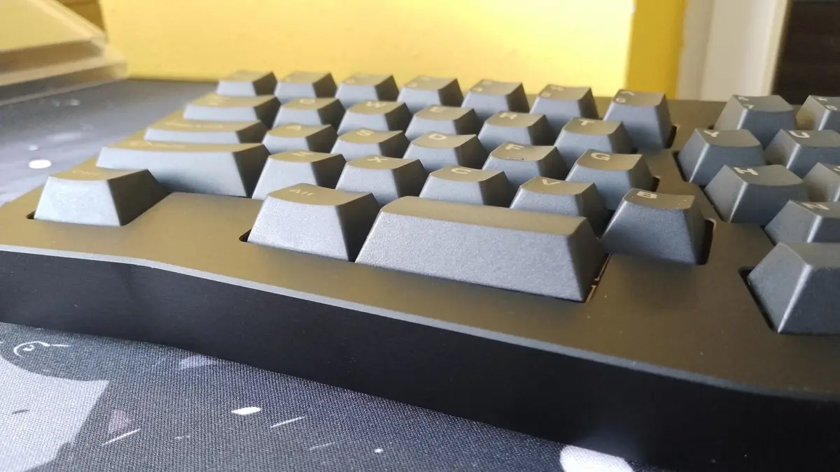 Zbliżenie z bliska na profil czarnej mechanicznej klawiatury Epomaker Tide Alice, pokazujące profil keycapów oraz aluminiową obudowę.